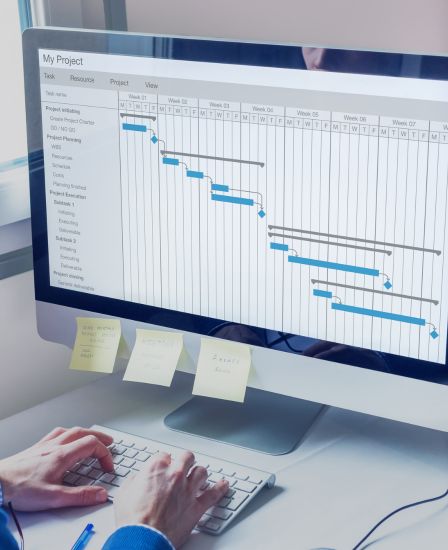 A person working at a computer with a Gantt graph up on the screen